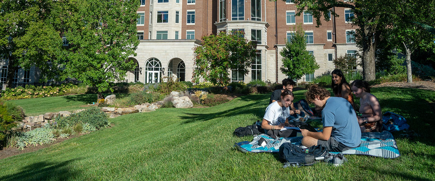 A group of students sit in the shade of a tree in Bear Creek Park