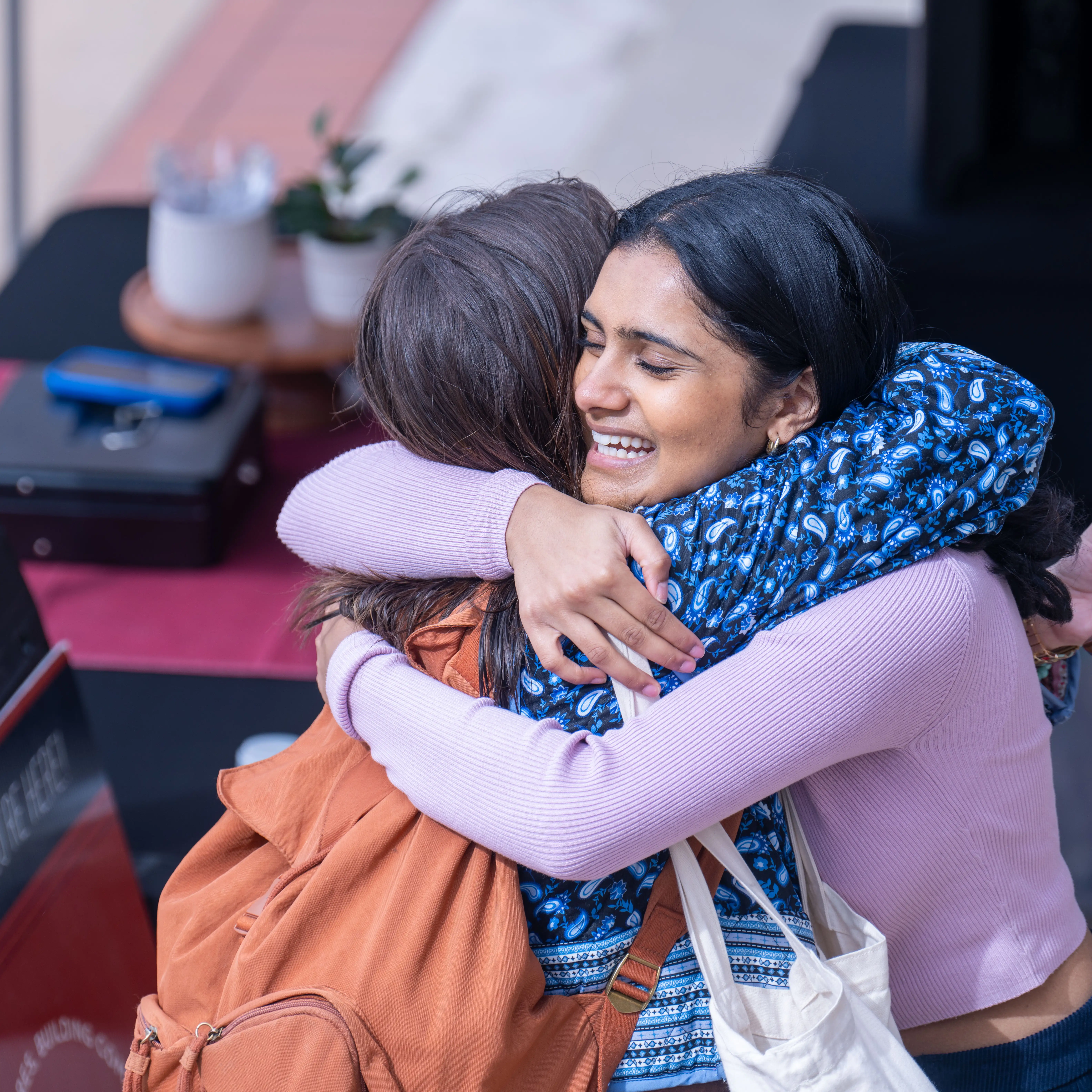 Two Belmont University students share a joyful hug during a campus event.