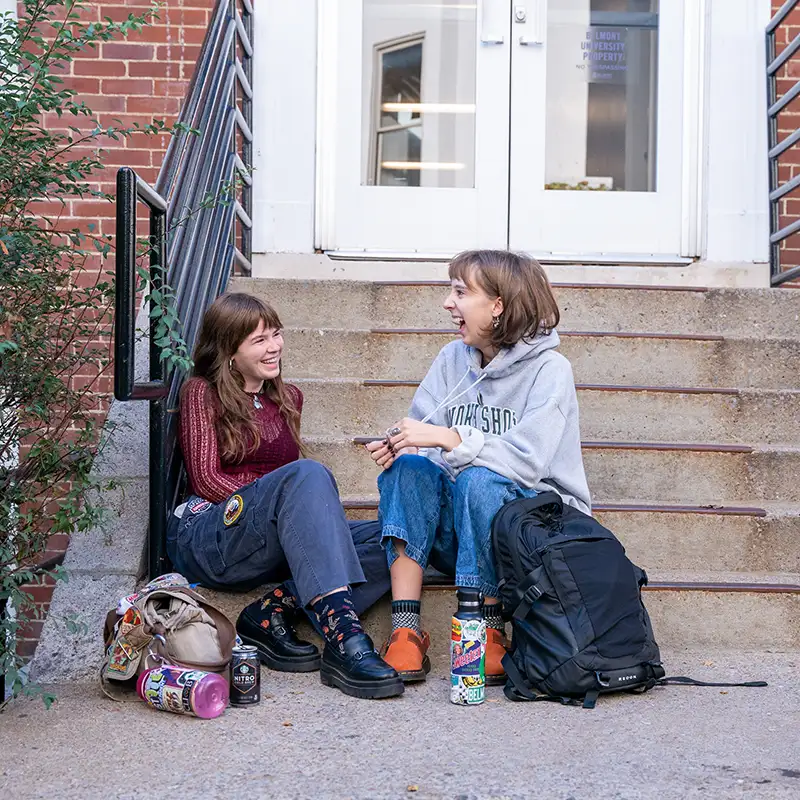 2 students sitting and laughing on the steps