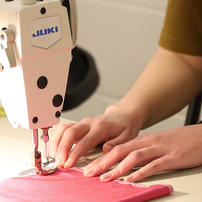 A close-up shot of a hand moving fabric through a sewing machine.