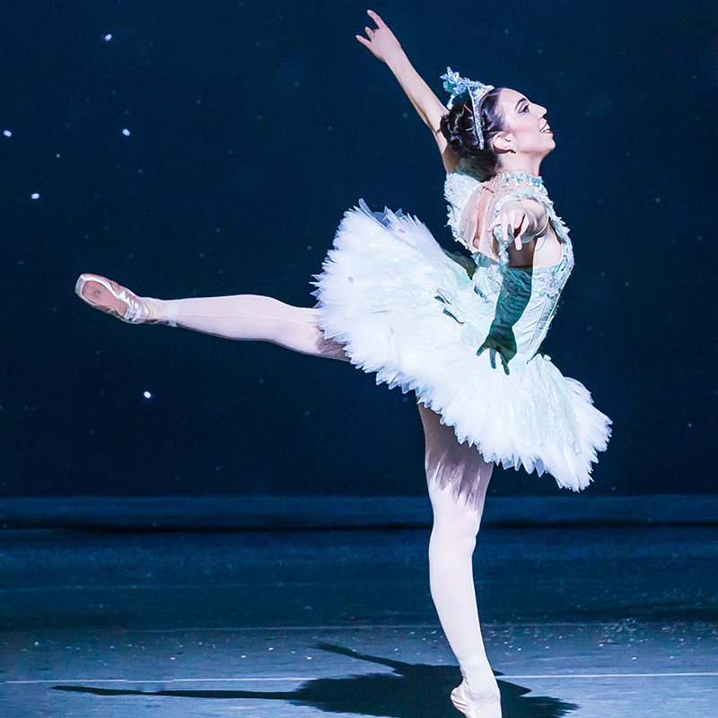 A female ballet dancer in a tutu dances on stage.