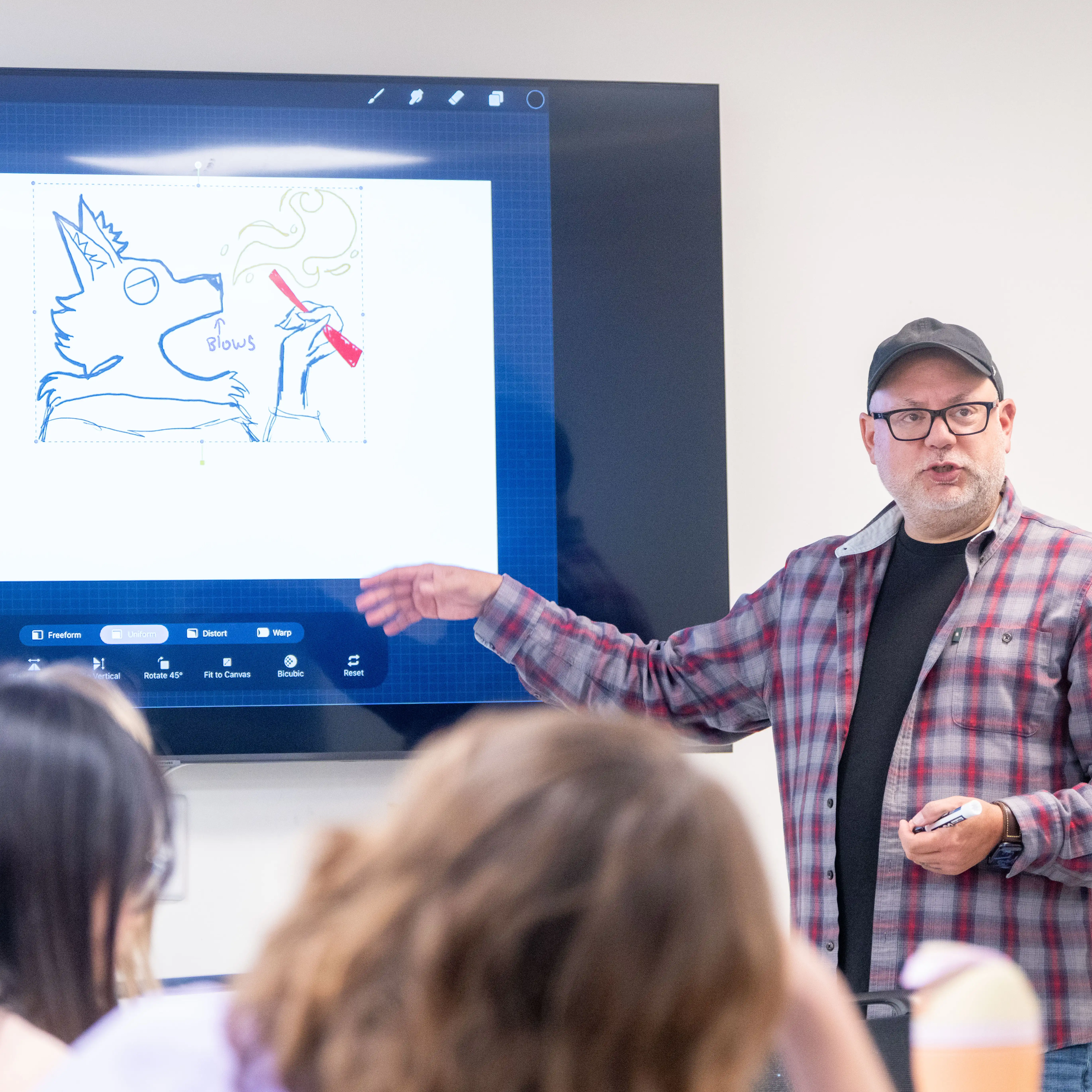 An instructor demonstrates digital animation techniques on an interactive display, guiding students through the principles of character design and frame-by-frame animation.