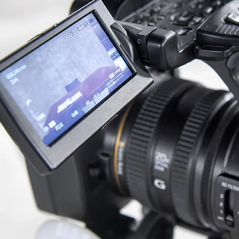 Close-up of a professional video camera with a viewfinder screen displaying a recording in progress.