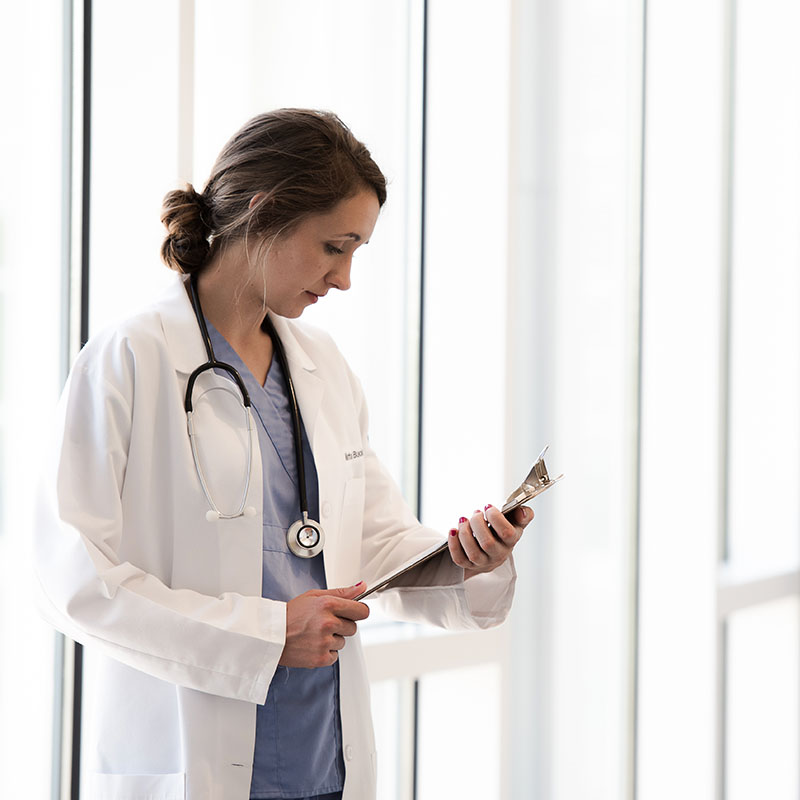 A nurse working with a clipboard next to a window