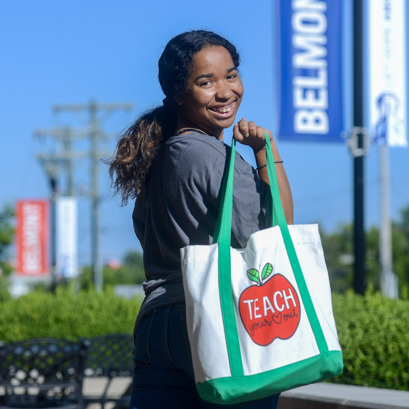 student smiles with a teach tote on her shoulder