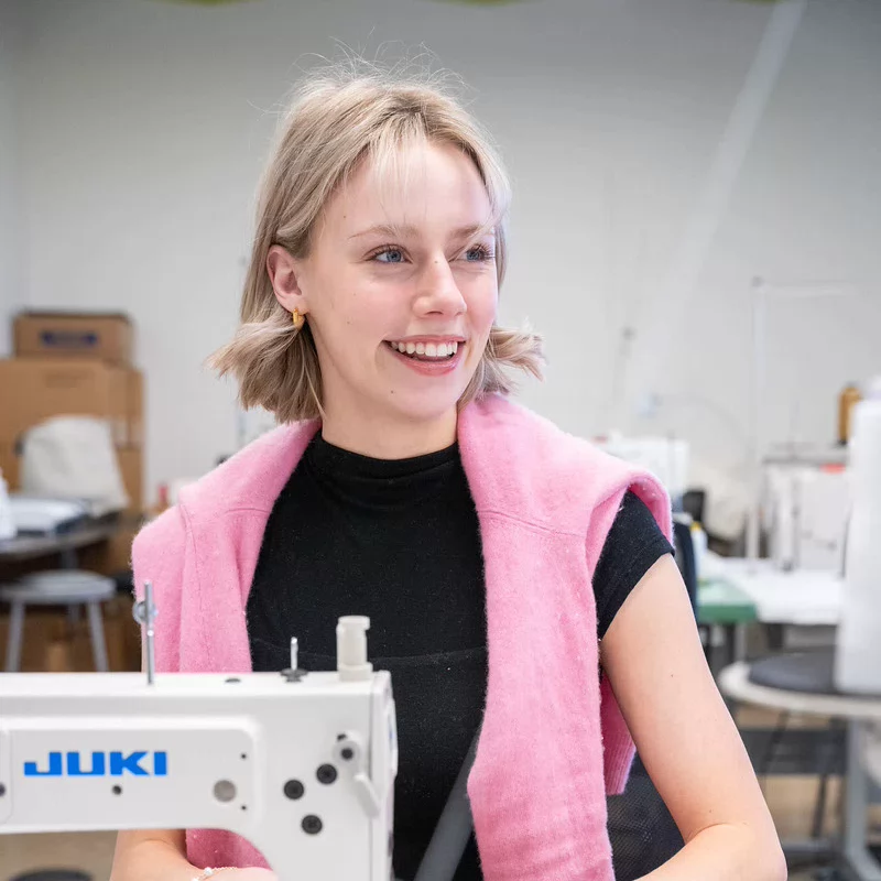 Fashion student uses an industrial sewing machine in a campus design studio.