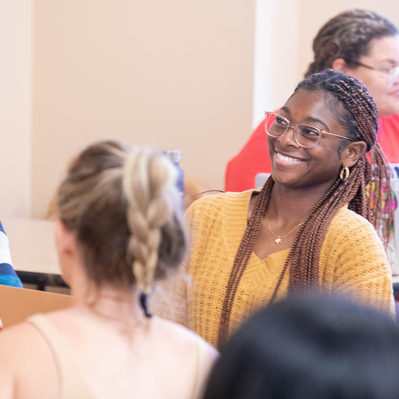 Student smiling while having group discussion in classroom