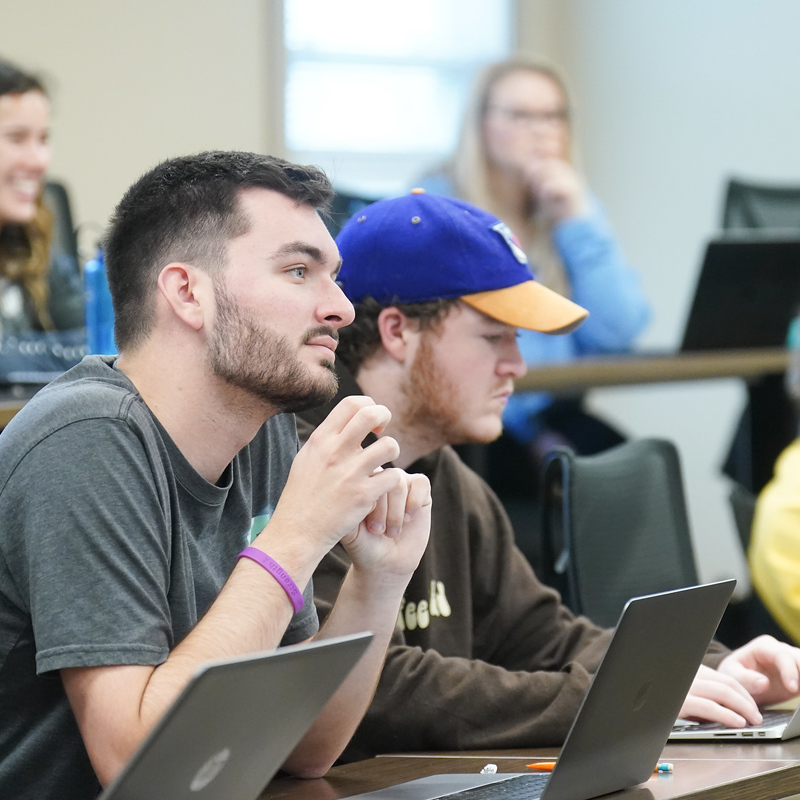 Students listening in class with laptops in front of them