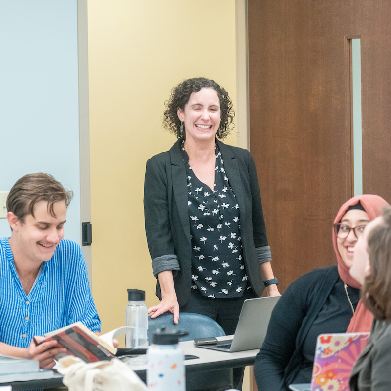 Professor laughing while having discussion with students in class room