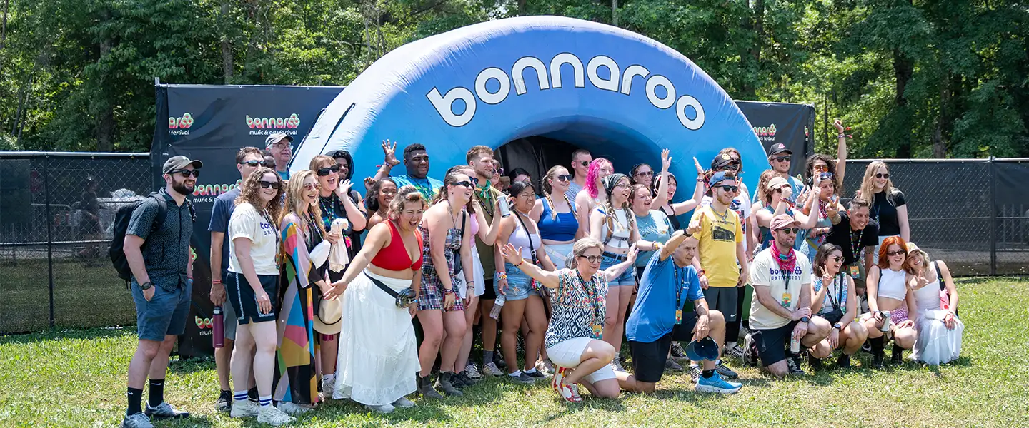 An outside image of a group of people standing in front of a Bonnaroo backdrop