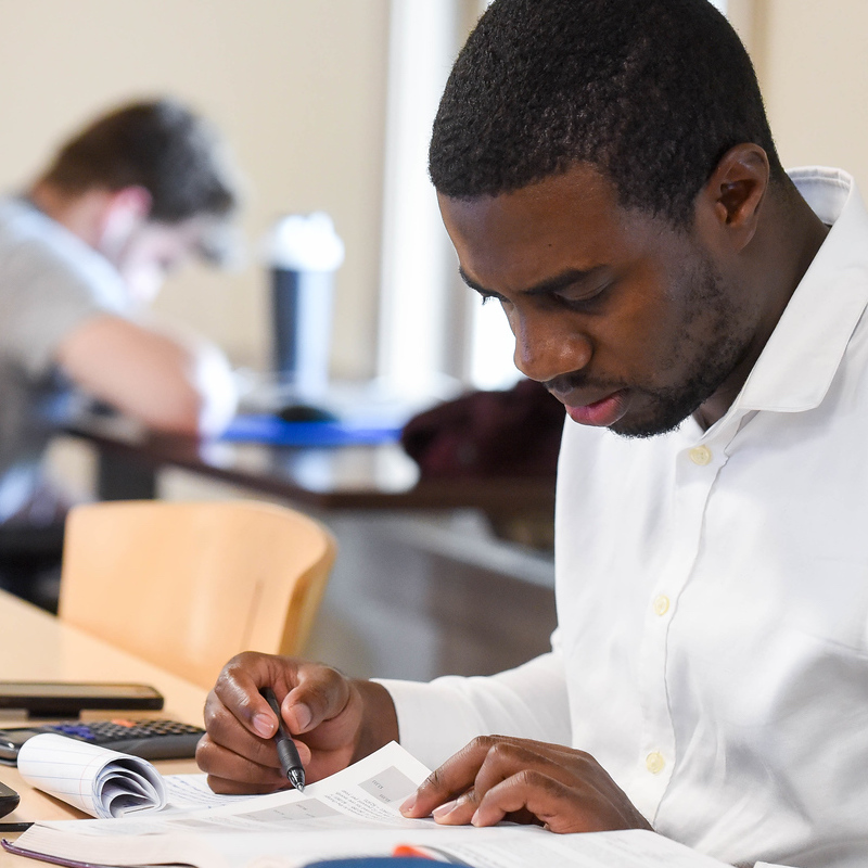 Student sitting in a study room, taking notes while reading