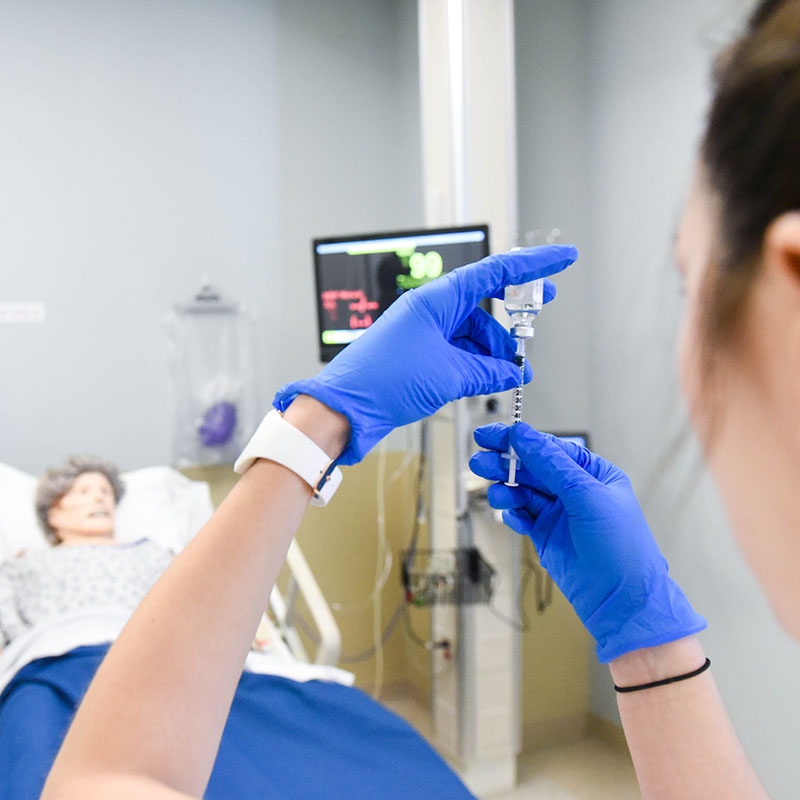 A nursing student drawing liquid into a syringe