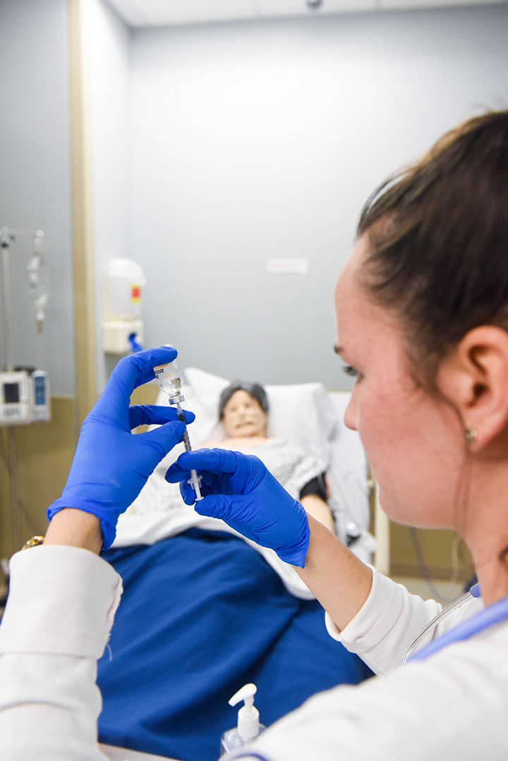 A nursing student drawing a syringe