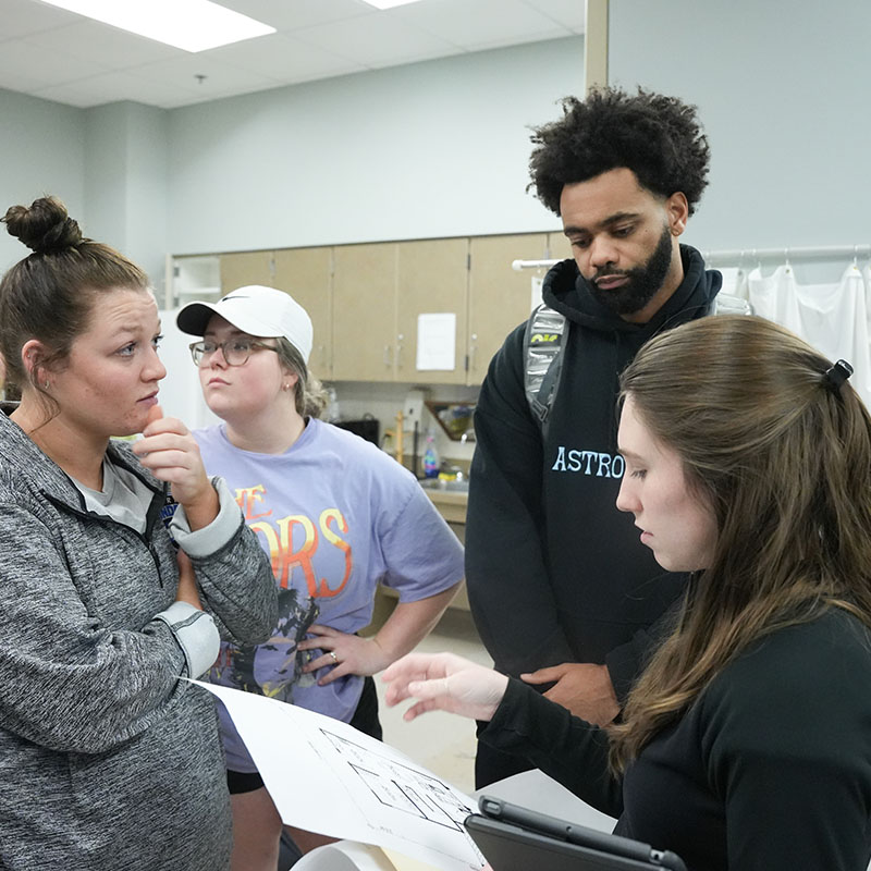 Occupational Therapy students standing a discussing a problem in lab