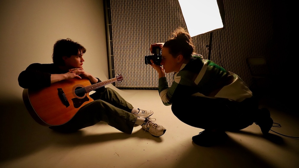 Elise Rowland. someone taking a picture of someone holding a guitar.