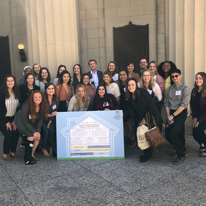 Social work students posing with a poster outlining a project they worked on