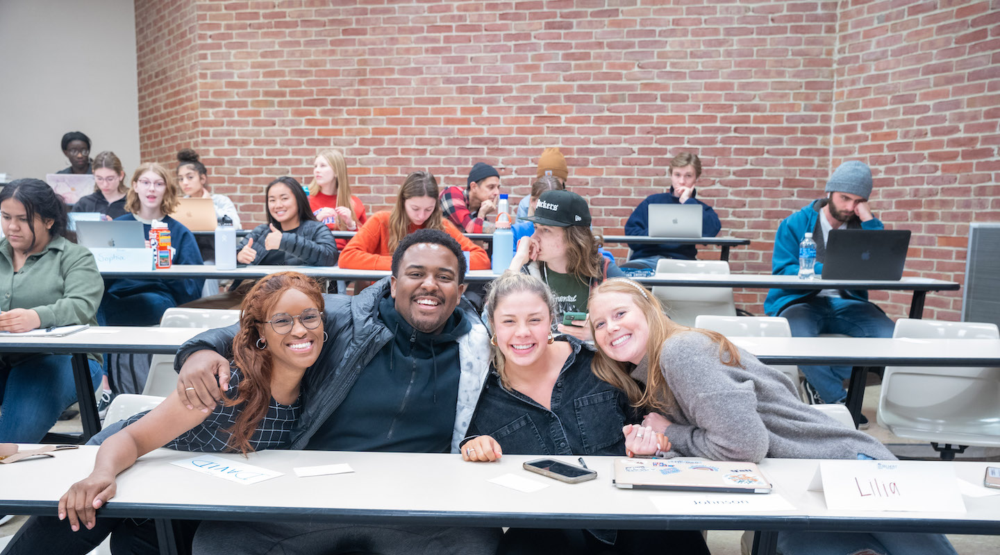 Five students with their arms around each other in the Bunch Multimedia Hall