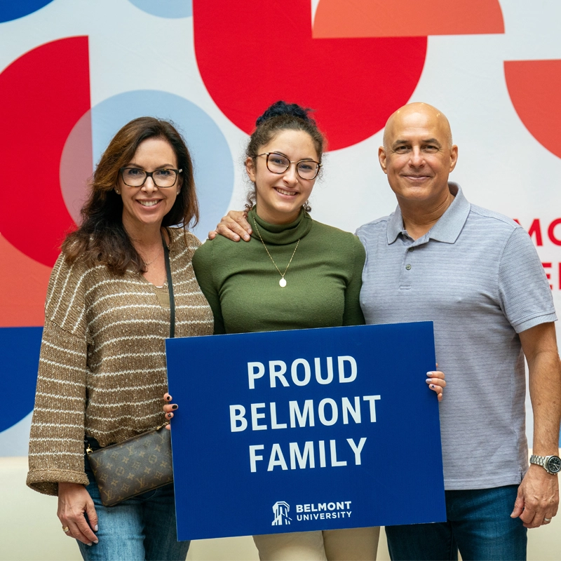 image of parents with their Belmont student holding a sign that says Proud Belmont family
