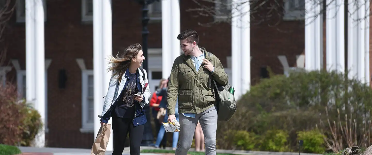 Two students walking across Belmont's Quad talking with each other