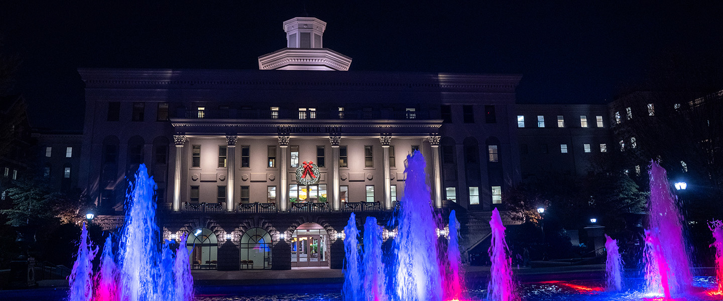 Belmont University at Christmas with a wreath on a columned building and a multiocolored fountain in front.