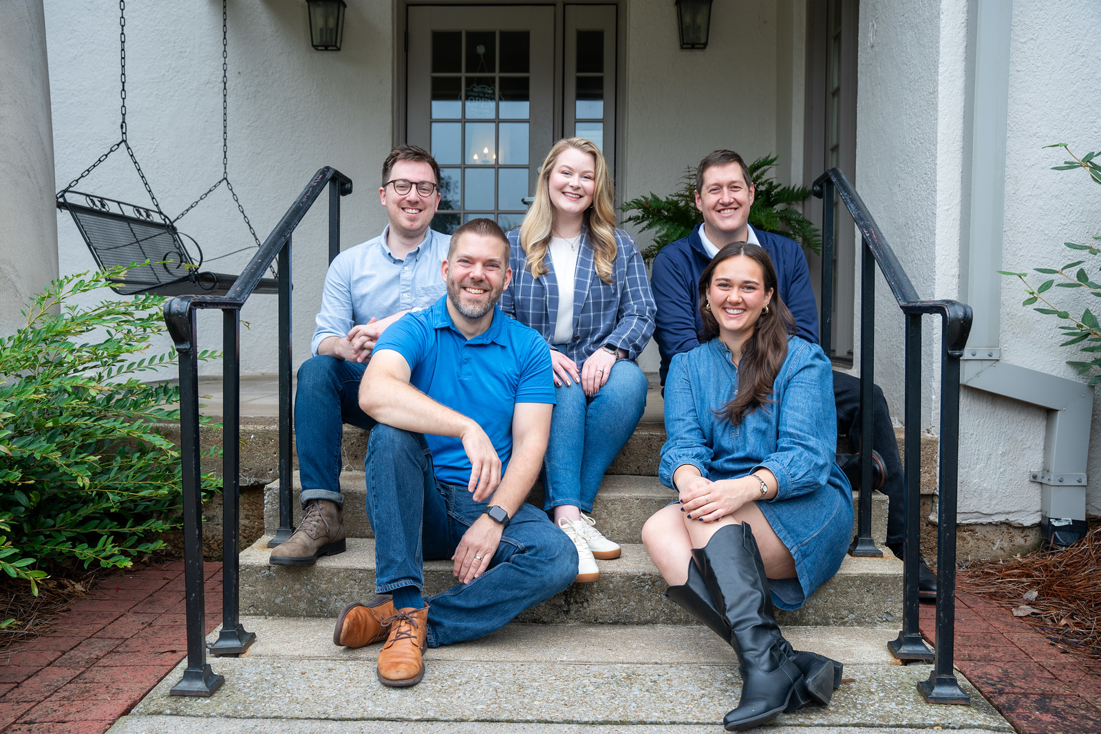 A photo of the Alumni Engagement team sitting on the front steps of the Foutch Alumni House