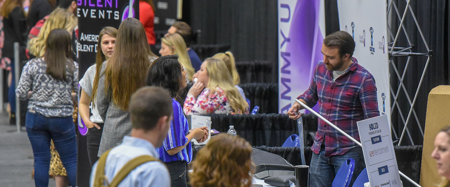 A wide view of a student talking to an employer at a job fair