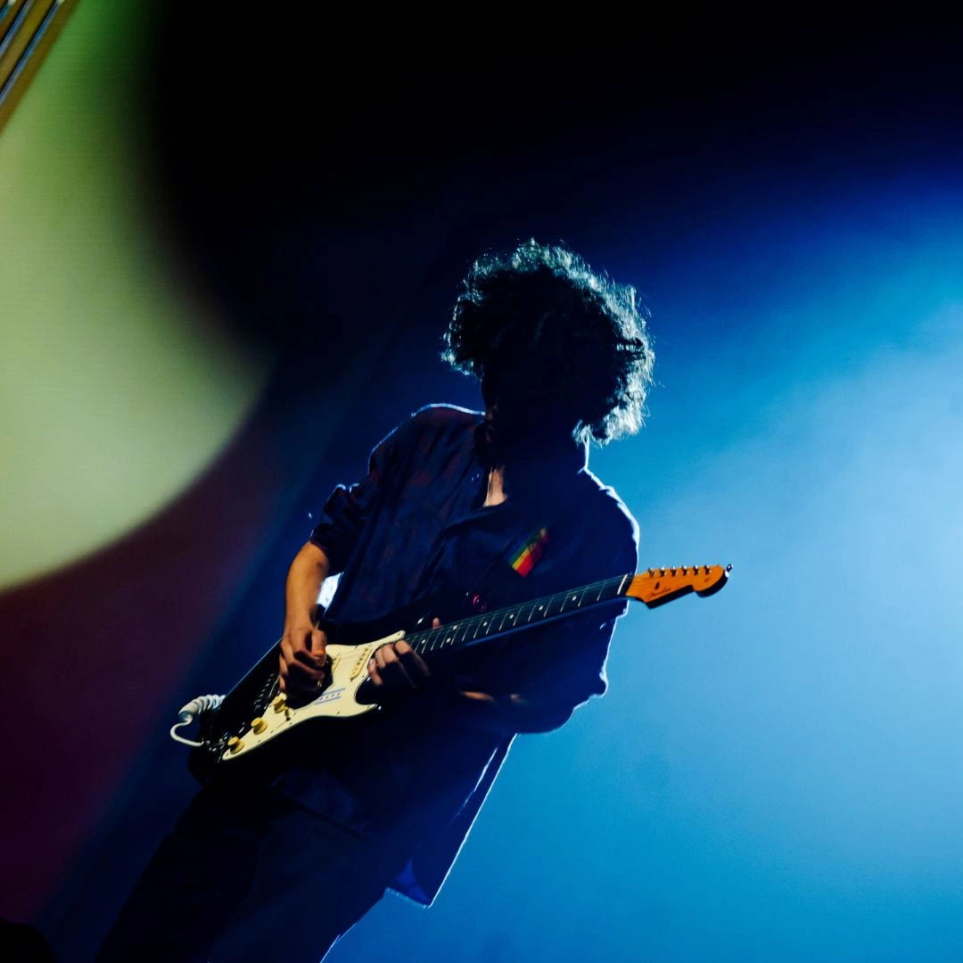 Frank Zappa performing on electric guitar under blue stage lighting during a concert performance.