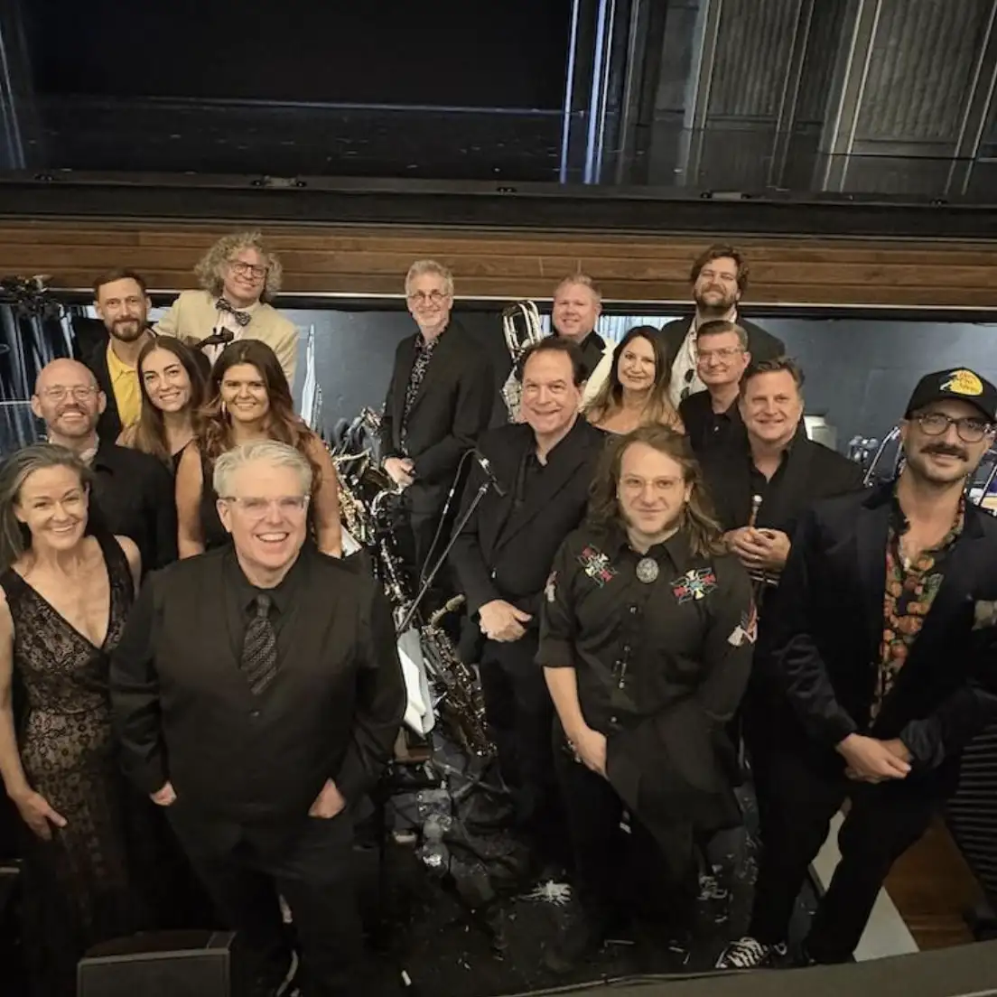 Jeff Cox and other musicians smiling for a group picture in an orchestra pit