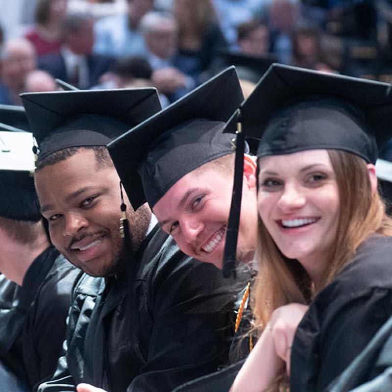 Students smiling for camera during graduation ceremony