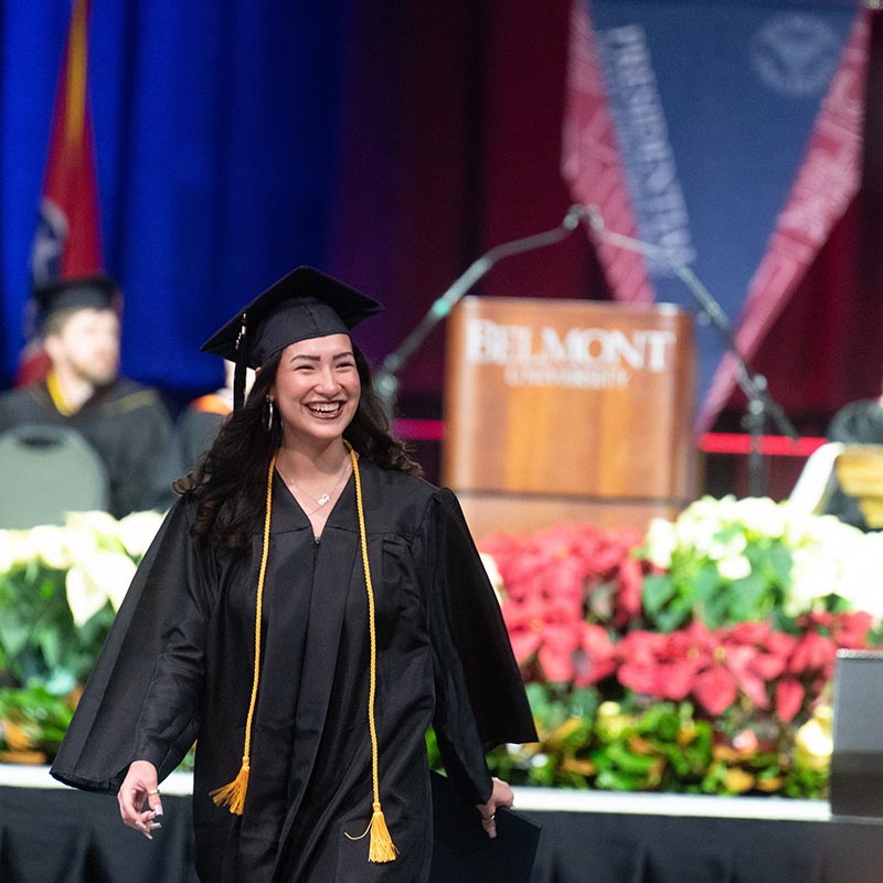 Student smiles in cap and gown during graduation ceremony after receiving diploma