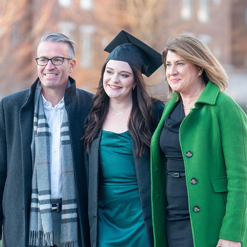 Graduate posing for a picture with their family before graduation ceremony