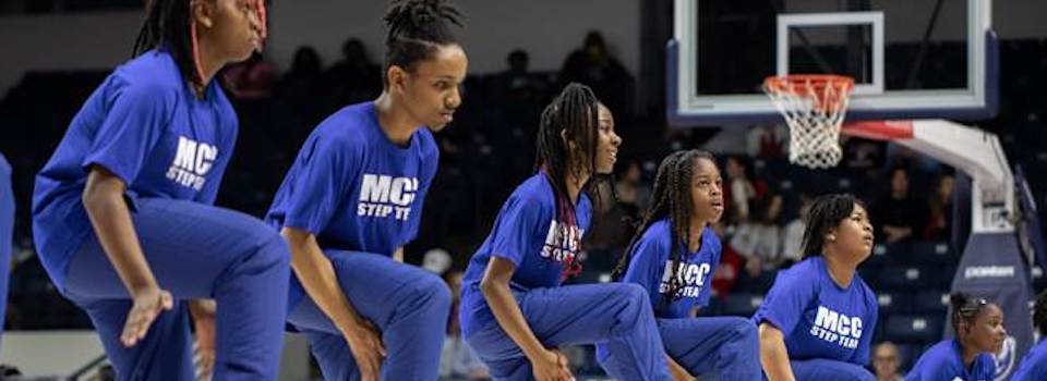 Group of female students perform a step routine.