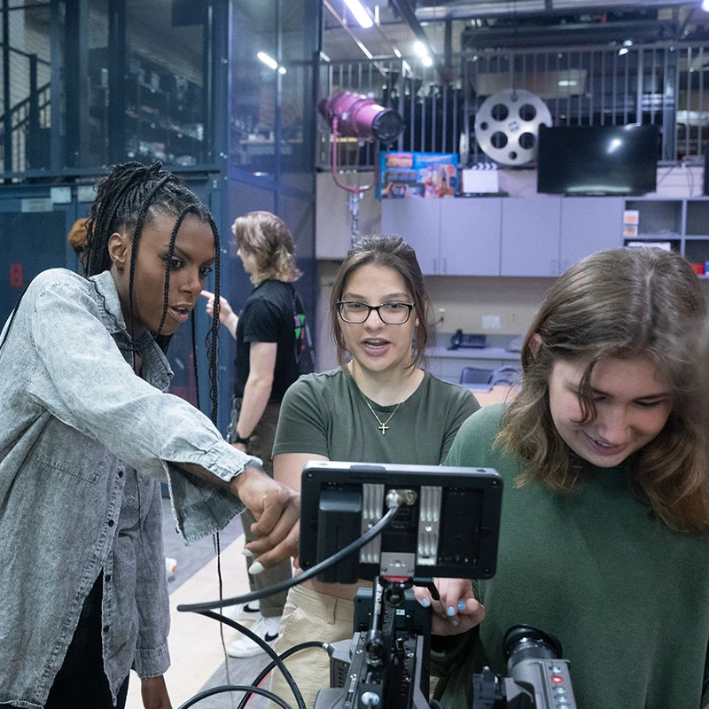 Two students work on a camera before a video shoot