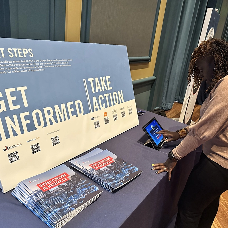 A woman looking at a presentation board that reads, Get Informed, Take Action