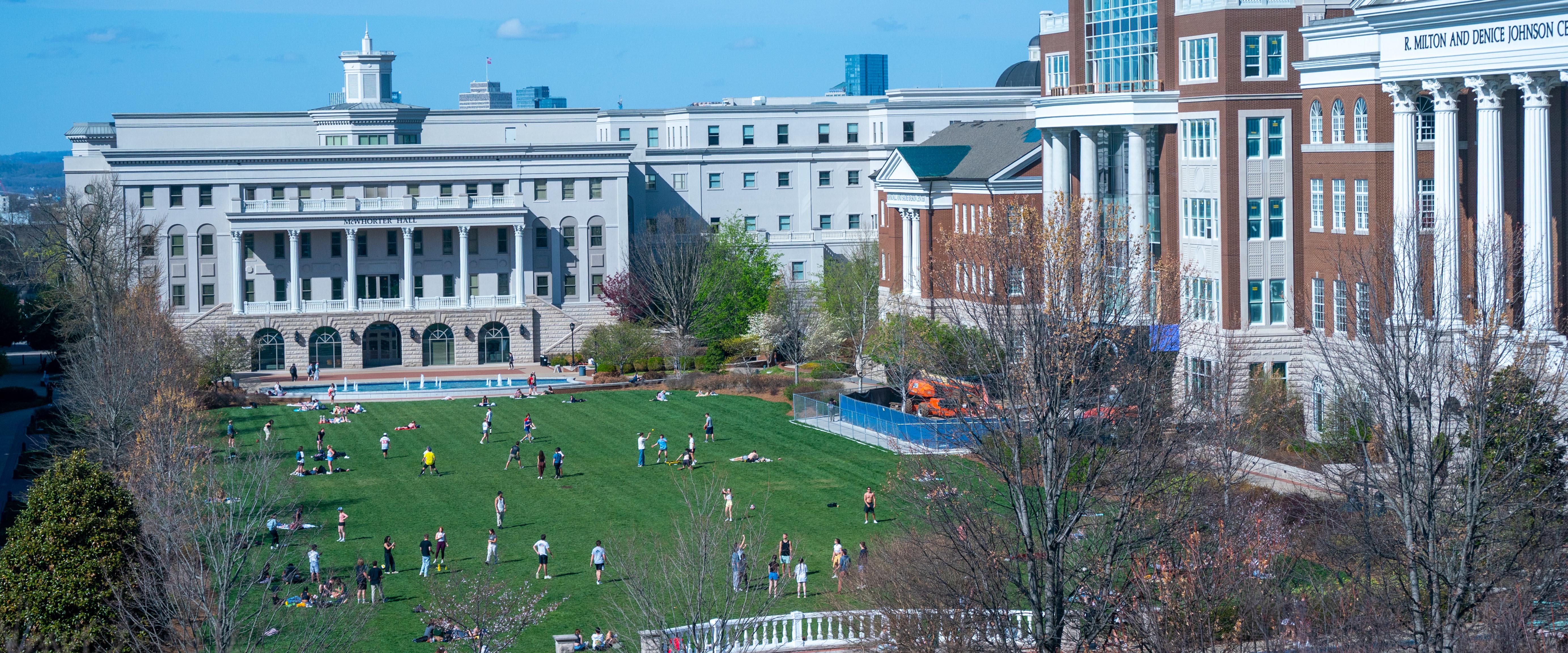 The main lawn on a sunny day with students playing games and studying on blankets 