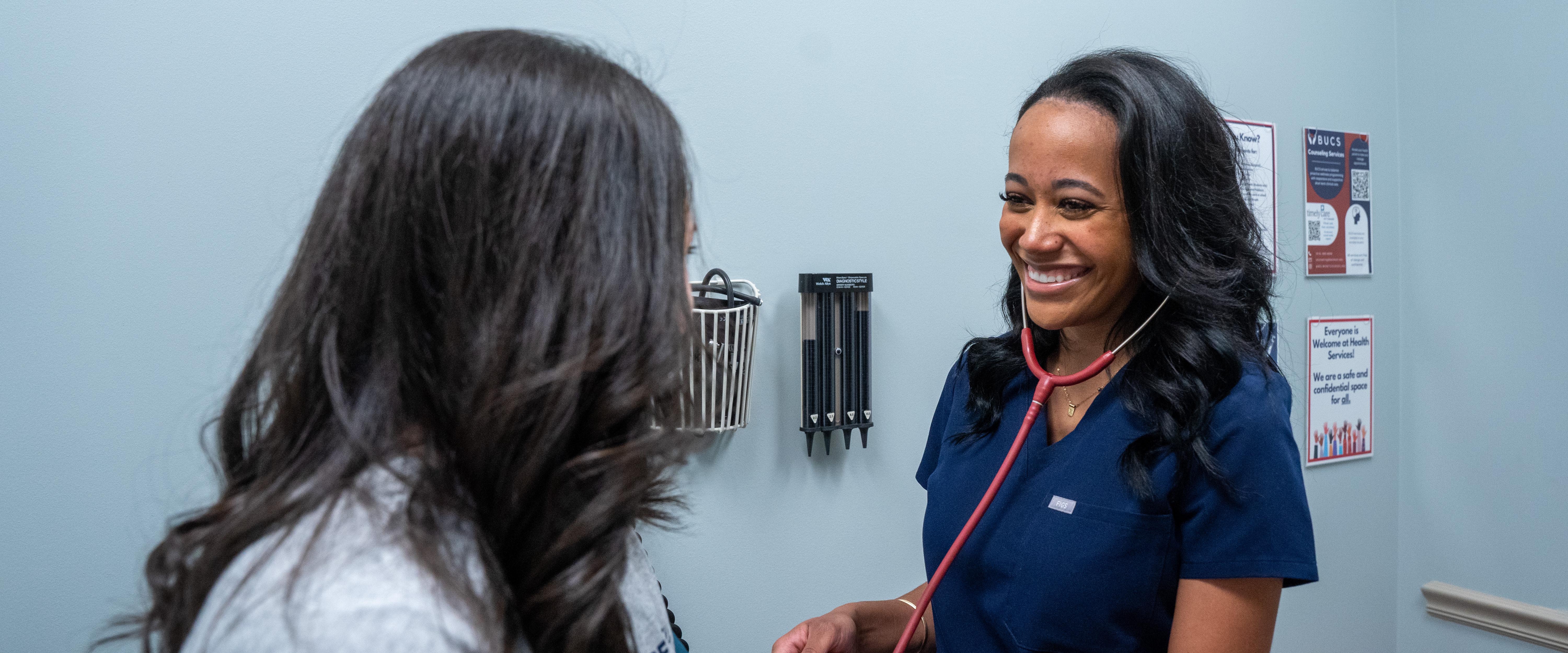 Nurse checking a patients blood pressure while listening through her stethoscope in the health services clinic room