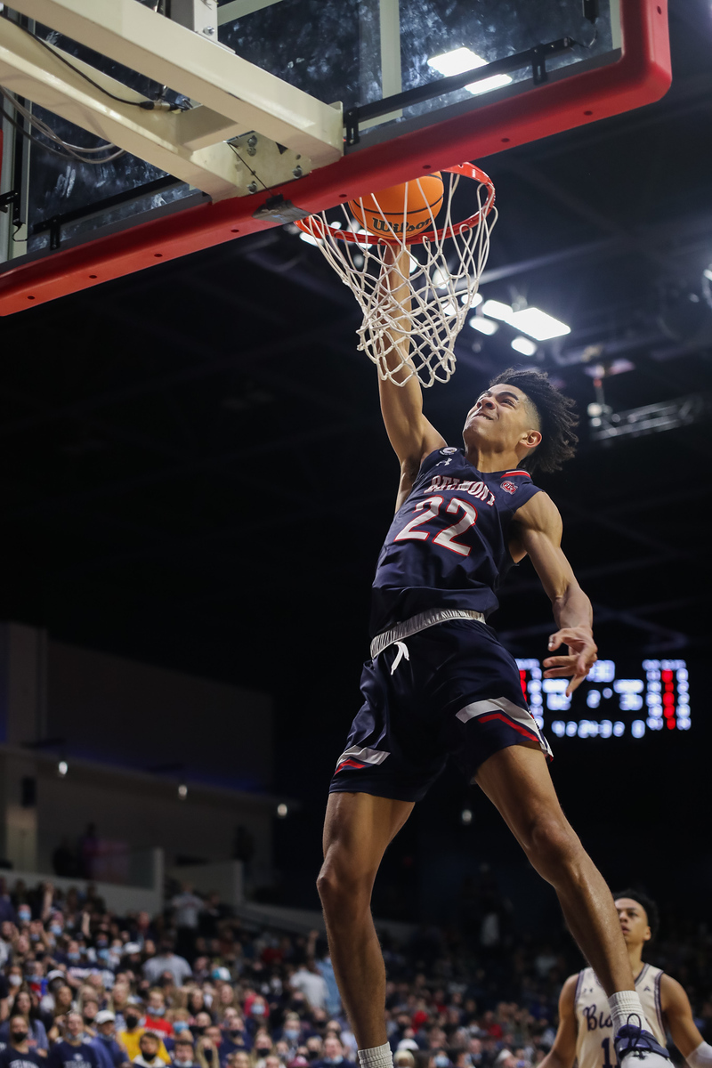 Belmont men's basketball player dunking a basketball over the head of a Lipscomb player