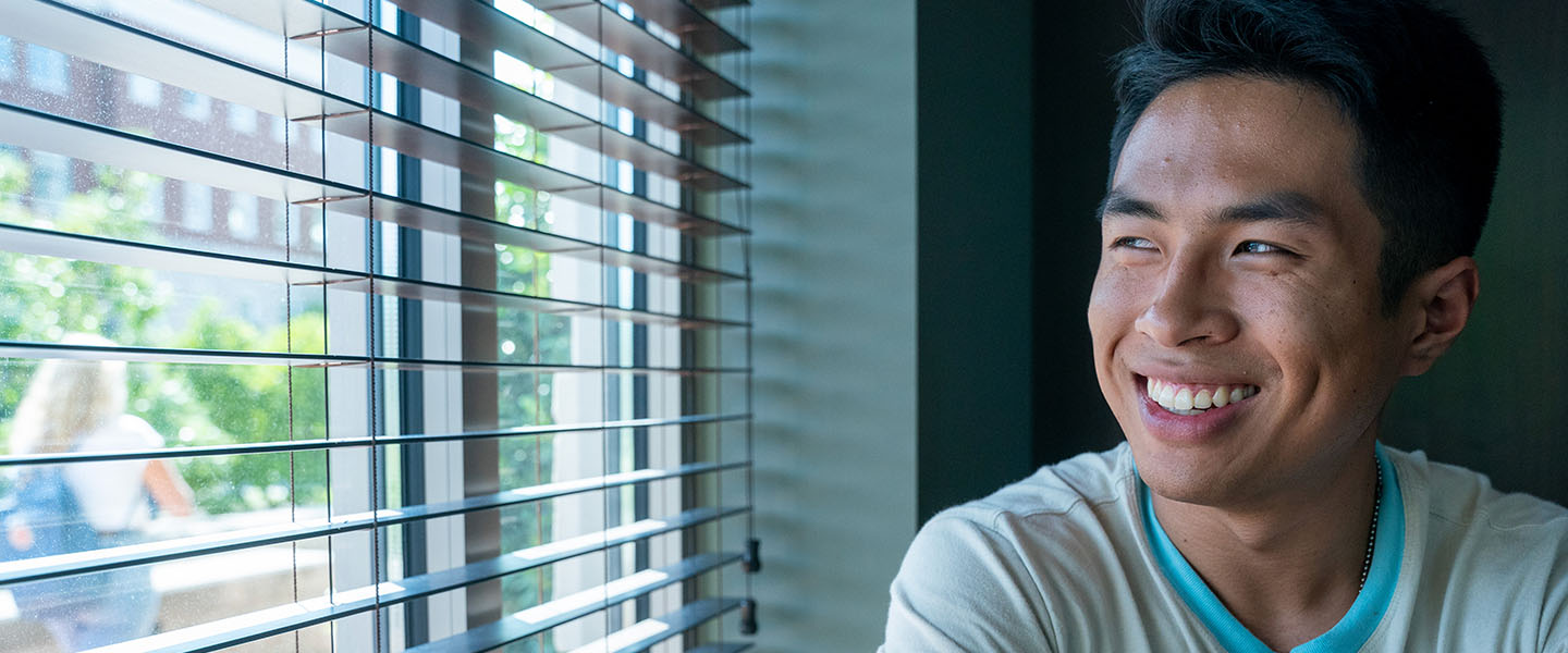 Student smiling as he looks out a window