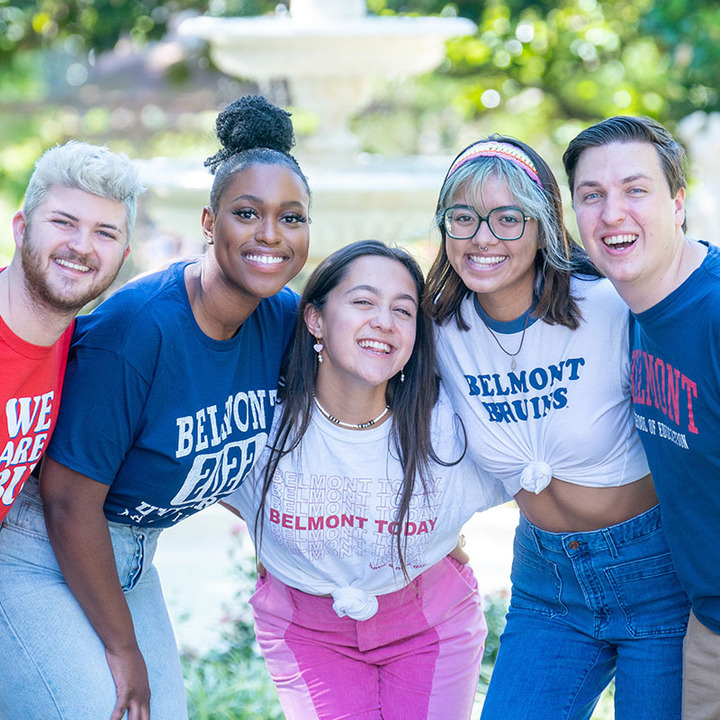 5 students happily smiling at the camera with a fountain in the background.