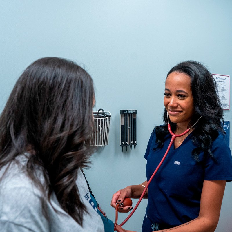 A nurse taking a student's blood pressure with a stethoscope