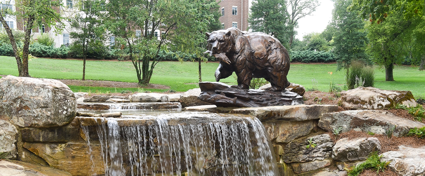 A statue of a bear with a fish in his mouth next to a Belmont fountain