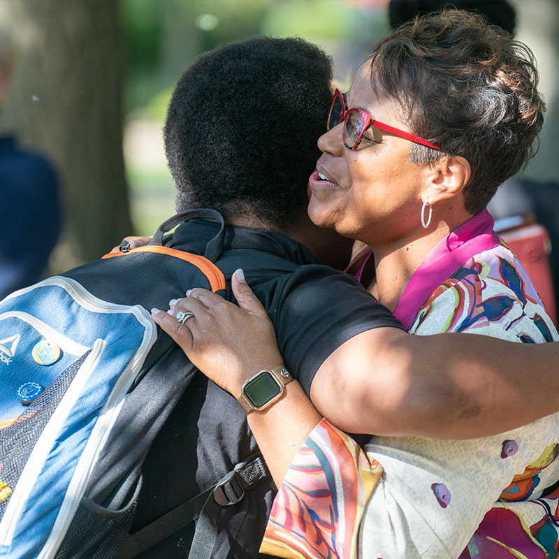 Dr. Susan West hugs a student at an event