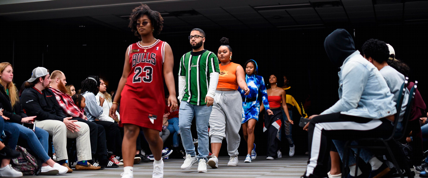 Models walk in Black history month fashion show while crowd watches