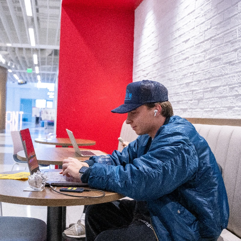 A young male Belmont student working on a laptop in the Jack C Massey Building