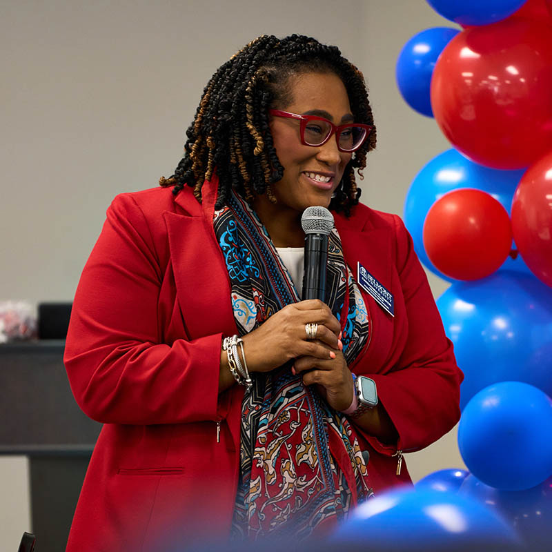 A woman smiling and speaking into a microphone