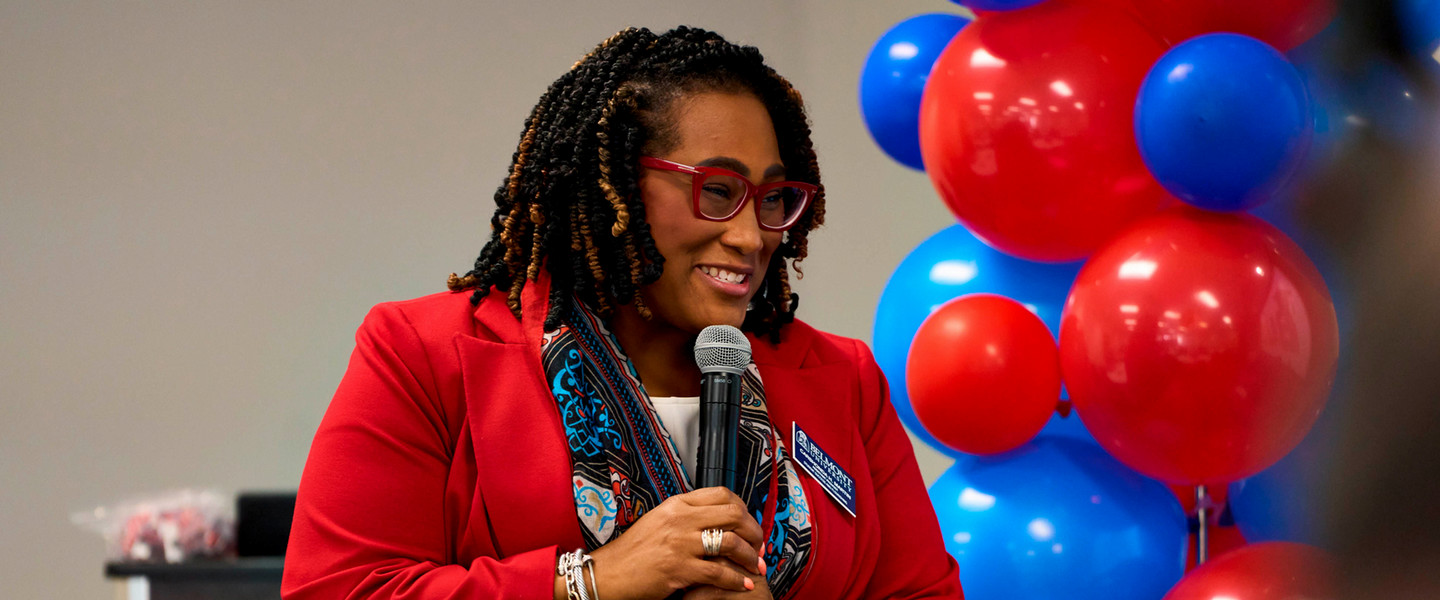 A woman smiling and speaking into a microphone