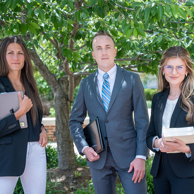 3 students standing outside under a tree