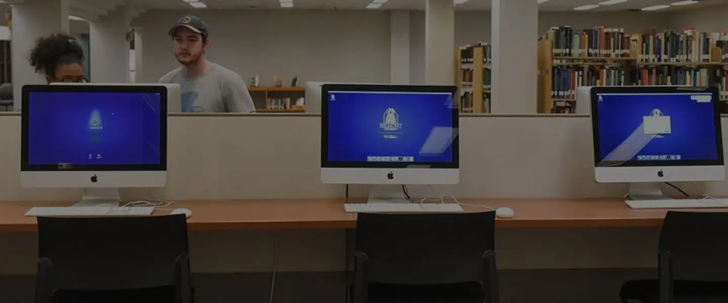 Computers on a table with students studying in the background out of focus