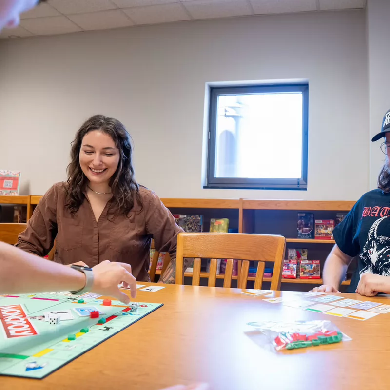 Library visitors smiling and playing Monopoly in Lila's Game Room.