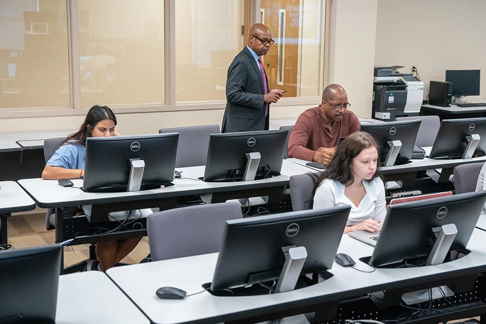 Massey classroom with students listening to professor while working on a computer